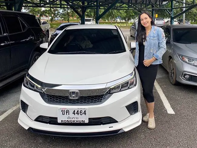 Customer standing next to a white Honda City rental car in Chiang Rai